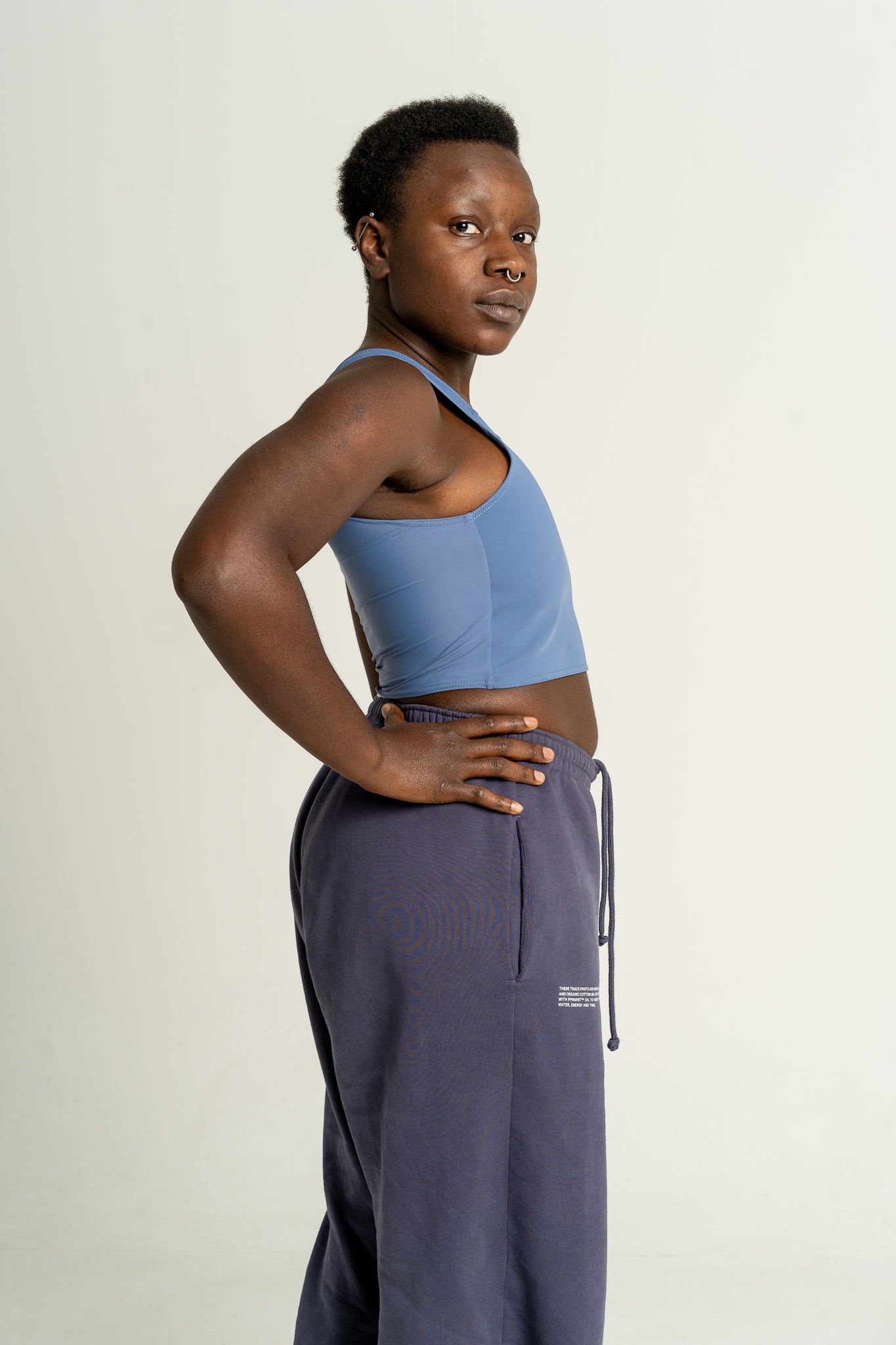 Person wearing an ocean blue coloured short chest binder and navy joggers against a white background