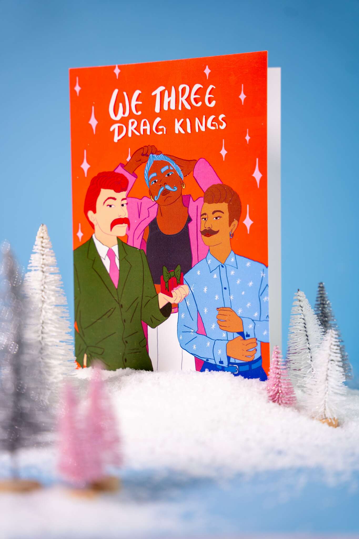 Christmas card with text 'We Three Drag Kings' with illustrated characters on a snowy landscape